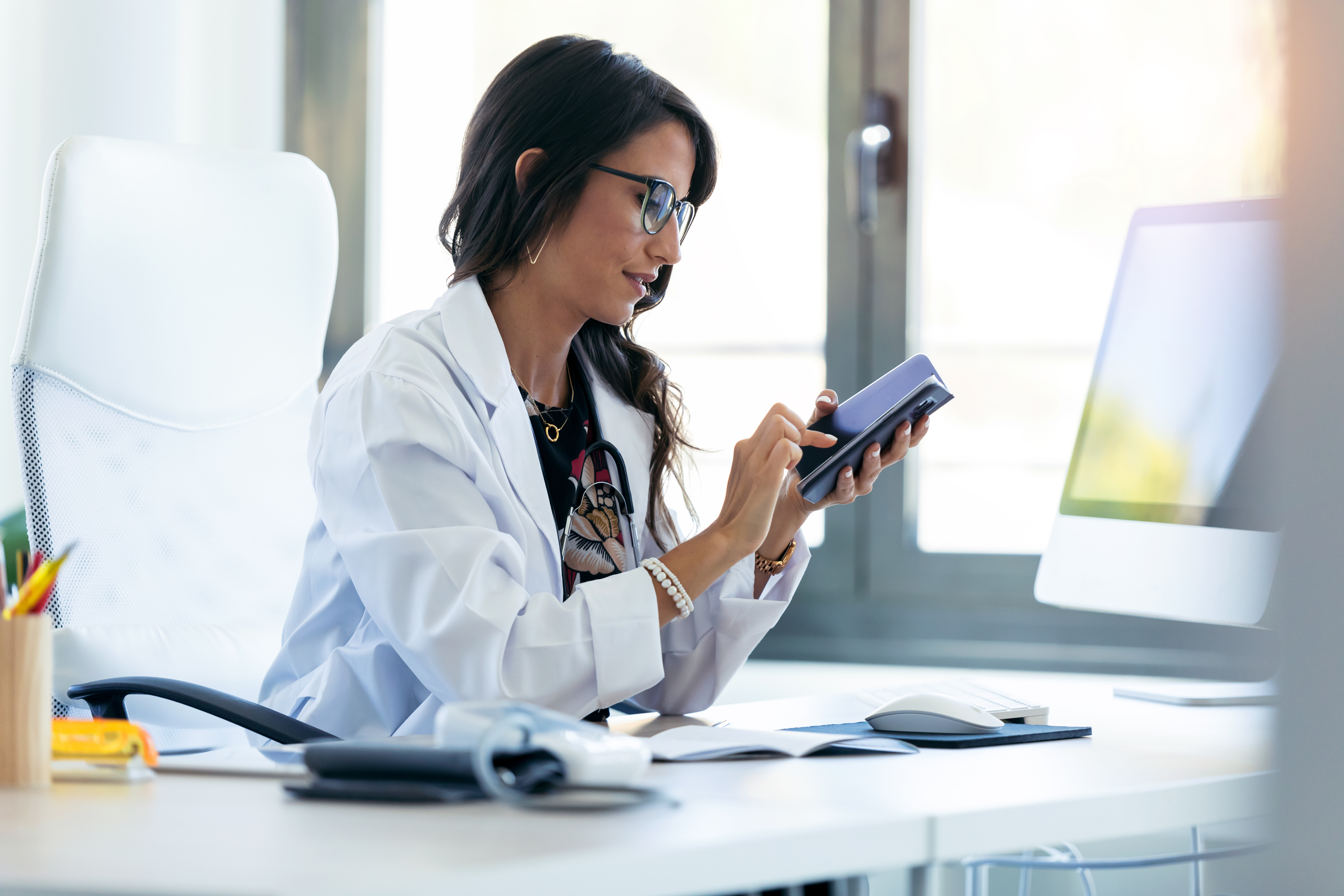 Doctor looking at phone at desk